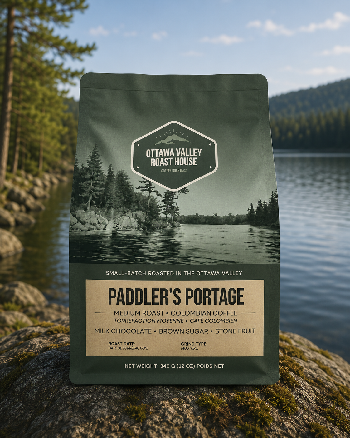 A bag of Ottawa Valley Roast House Paddler's Portage coffee stands upright on a mossy log outdoors, with a lake, trees, and mountains blurred in the background.