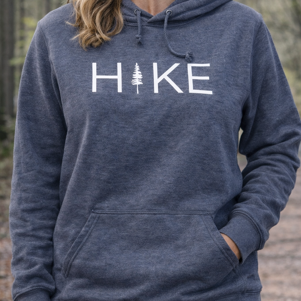 Person wearing a navy hoodie with 'HIKE' and a tree graphic outdoors.